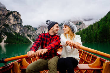Beautiful couple of young adults visiting an alpine lake at Braies, Italy - Tourists with hiking outfit having fun on vacation during autumn foliage - Concepts about travel, lifestyle and wanderlust - DMDF01215