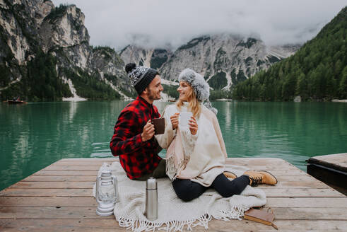 Beautiful couple of young adults visiting an alpine lake at Braies, Italy - Tourists with hiking outfit having fun on vacation during autumn foliage - Concepts about travel, lifestyle and wanderlust - DMDF01238