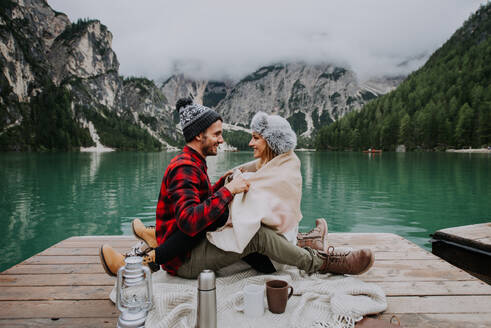 Beautiful couple of young adults visiting an alpine lake at Braies, Italy - Tourists with hiking outfit having fun on vacation during autumn foliage - Concepts about travel, lifestyle and wanderlust - DMDF01239