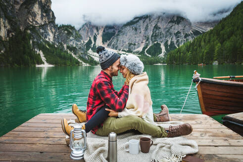 Beautiful couple of young adults visiting an alpine lake at Braies, Italy - Tourists with hiking outfit having fun on vacation during autumn foliage - Concepts about travel, lifestyle and wanderlust - DMDF01240