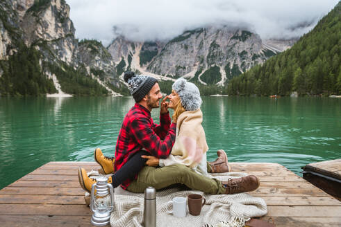 Beautiful couple of young adults visiting an alpine lake at Braies, Italy - Tourists with hiking outfit having fun on vacation during autumn foliage - Concepts about travel, lifestyle and wanderlust - DMDF01241