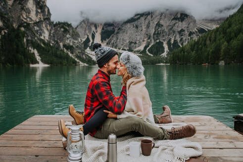 Beautiful couple of young adults visiting an alpine lake at Braies, Italy - Tourists with hiking outfit having fun on vacation during autumn foliage - Concepts about travel, lifestyle and wanderlust - DMDF01242