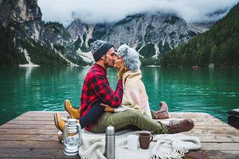 Beautiful couple of young adults visiting an alpine lake at Braies, Italy - Tourists with hiking outfit having fun on vacation during autumn foliage - Concepts about travel, lifestyle and wanderlust - DMDF01243