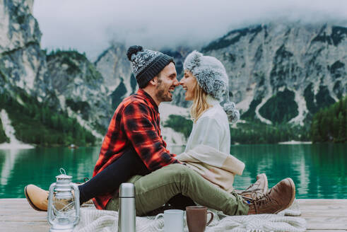 Beautiful couple of young adults visiting an alpine lake at Braies, Italy - Tourists with hiking outfit having fun on vacation during autumn foliage - Concepts about travel, lifestyle and wanderlust - DMDF01248