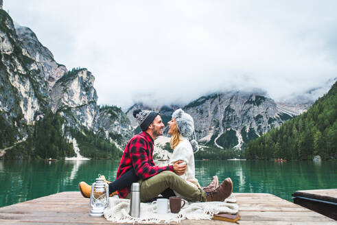 Beautiful couple of young adults visiting an alpine lake at Braies, Italy - Tourists with hiking outfit having fun on vacation during autumn foliage - Concepts about travel, lifestyle and wanderlust - DMDF01249