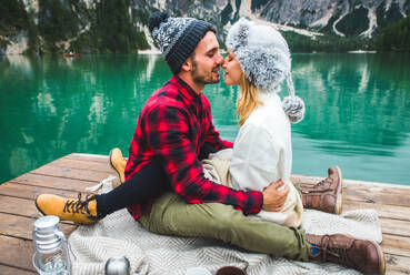 Beautiful couple of young adults visiting an alpine lake at Braies, Italy - Tourists with hiking outfit having fun on vacation during autumn foliage - Concepts about travel, lifestyle and wanderlust - DMDF01250