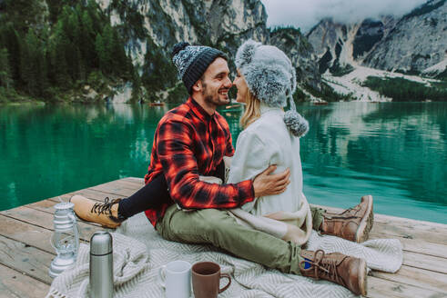 Beautiful couple of young adults visiting an alpine lake at Braies, Italy - Tourists with hiking outfit having fun on vacation during autumn foliage - Concepts about travel, lifestyle and wanderlust - DMDF01253