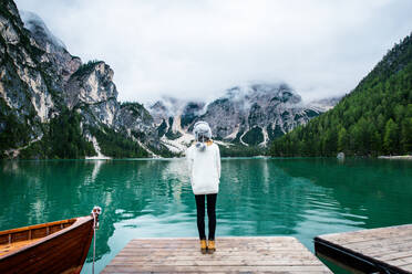 Beautiful woman visiting an alpine lake at Braies, Italy - Tourist with hiking outfit having fun on vacation during autumn foliage - Concepts about travel, lifestyle and wanderlust - DMDF01259