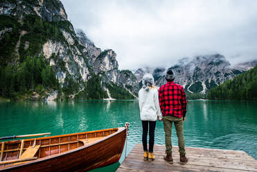 Beautiful couple of young adults visiting an alpine lake at Braies, Italy - Tourists with hiking outfit having fun on vacation during autumn foliage - Concepts about travel, lifestyle and wanderlust - DMDF01261