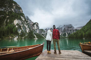 Beautiful couple of young adults visiting an alpine lake at Braies, Italy - Tourists with hiking outfit having fun on vacation during autumn foliage - Concepts about travel, lifestyle and wanderlust - DMDF01262