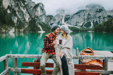 Beautiful couple of young adults visiting an alpine lake at Braies, Italy - Tourists with hiking outfit having fun on vacation during autumn foliage - Concepts about travel, lifestyle and wanderlust - DMDF01281