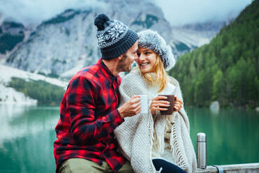 Beautiful couple of young adults visiting an alpine lake at Braies, Italy - Tourists with hiking outfit having fun on vacation during autumn foliage - Concepts about travel, lifestyle and wanderlust - DMDF01285