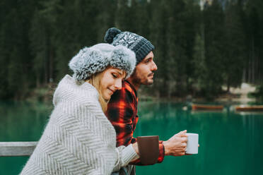 Beautiful couple of young adults visiting an alpine lake at Braies, Italy - Tourists with hiking outfit having fun on vacation during autumn foliage - Concepts about travel, lifestyle and wanderlust - DMDF01287