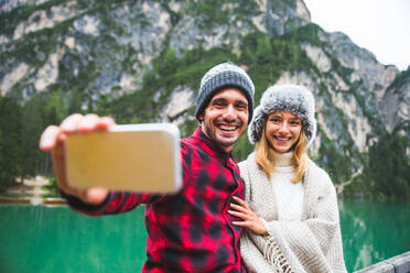 Hübsches Paar junger Erwachsener beim Besuch eines Bergsees in Prags, Italien - Touristen in Wanderkleidung haben Spaß im Urlaub während des Herbstlaubs - Konzepte über Reisen, Lebensstil und Fernweh - DMDF01289