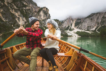 Beautiful couple of young adults visiting an alpine lake at Braies, Italy - Tourists with hiking outfit having fun on vacation during autumn foliage - Concepts about travel, lifestyle and wanderlust - DMDF01291