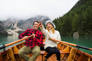 Beautiful couple of young adults visiting an alpine lake at Braies, Italy - Tourists with hiking outfit having fun on vacation during autumn foliage - Concepts about travel, lifestyle and wanderlust - DMDF01304