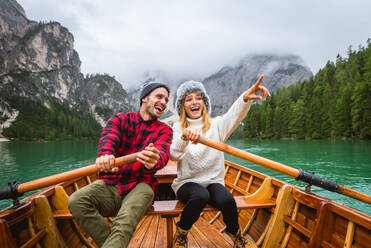 Beautiful couple of young adults visiting an alpine lake at Braies, Italy - Tourists with hiking outfit having fun on vacation during autumn foliage - Concepts about travel, lifestyle and wanderlust - DMDF01305