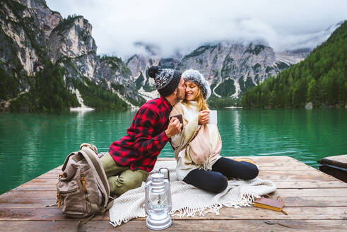 Beautiful couple of young adults visiting an alpine lake at Braies, Italy - Tourists with hiking outfit having fun on vacation during autumn foliage - Concepts about travel, lifestyle and wanderlust - DMDF01318