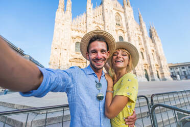 Beautiful couple of lovers sightseeing in Italy - Playful tourists visiting the Duomo cathedral in Milan - DMDF01356