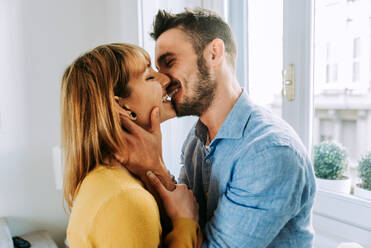 Two young adults at home - Romantic moment at home, couple of lovers kissing - DMDF01358