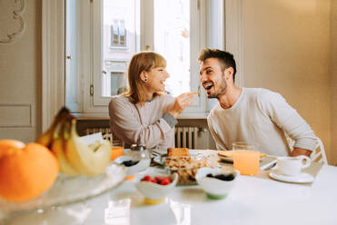 Two young adults at home - Beautiful couple of lovers having breakfast in the morning - DMDF01372