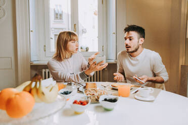 Two young adults at home - Beautiful couple of lovers having a discussion about betrayal with smartphone - DMDF01375