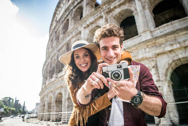 Young couple at the Colosseum, Rome - Happy tourists visiting italian famous landmarks - DMDF01397