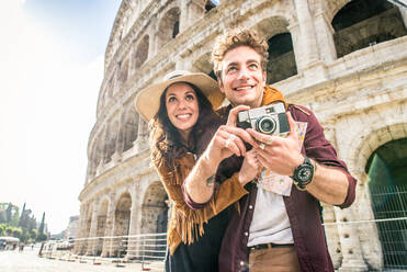 Young couple at the Colosseum, Rome - Happy tourists visiting italian famous landmarks - DMDF01398