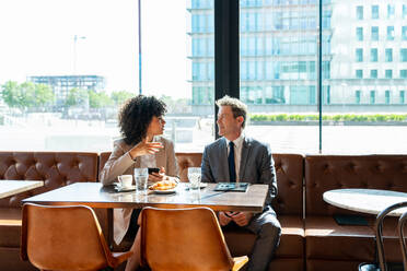 Senior businessman and beautiful hispanic businesswoman meeting in a bar restaurant - Two colleagues bonding in a cafe after work - DMDF01399