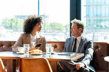 Senior businessman and beautiful hispanic businesswoman meeting in a bar restaurant - Two colleagues bonding in a cafe after work - DMDF01400