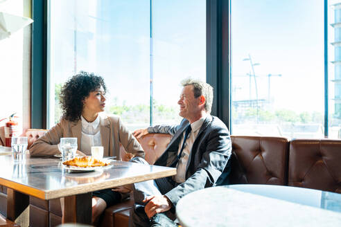 Senior businessman and beautiful hispanic businesswoman meeting in a bar restaurant - Two colleagues bonding in a cafe after work - DMDF01403