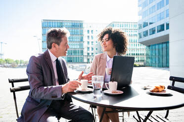 Senior businessman and beautiful hispanic businesswoman meeting in a bar restaurant - Two colleagues bonding in a cafe after work - DMDF01405