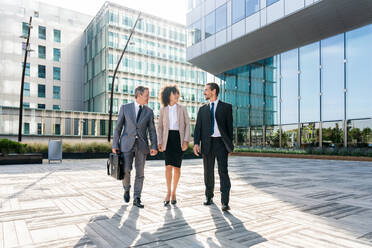 Multiracial group of business people bonding outdoors - International business corporate team wearing elegant suit meeting in a business park - DMDF01421