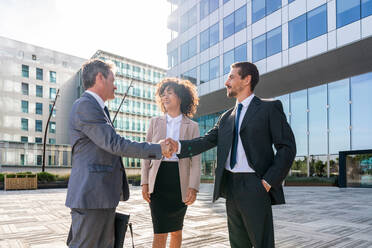 Multiracial group of business people bonding outdoors - International business corporate team wearing elegant suit meeting in a business park - DMDF01423