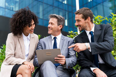 Multiracial group of business people bonding outdoors - International business corporate team wearing elegant suit meeting in a business park - DMDF01444