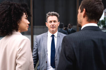 Multiracial group of business people bonding outdoors - International business corporate team wearing elegant suit meeting in a business park - DMDF01447