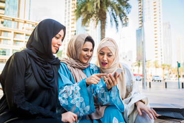 Arabische Frauen mit Abaya, die sich treffen und Spaß im Freien haben - Glückliche mittelöstliche Freunde, die sich beim Einkaufen treffen und unterhalten - DMDF01464