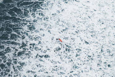 Aerial view of a surfer in the foam of the waves in Famara beach, Lanzarote, Spain. - AAEF19538