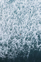 Aerial view of a surfer in the foam of the waves, Lanzarote, Spain. - AAEF19542