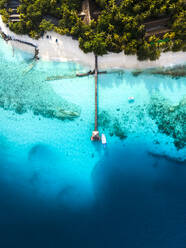 Luftaufnahme eines Bootes am Ende des Piers und der Uferpromenade auf einer Insel im kristallklaren blauen Ozean, Baa Atoll, Malediven. - AAEF20073