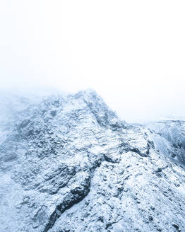 Aerial view of the Blue Mountains peak covered with snow and ice during a foggy day in winter, Kopavogur, Iceland. - AAEF20116