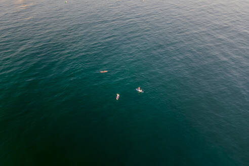 Aerial view of people doing kayak at sunset along the coastline in Sitges, Barcelona, Spain. - AAEF20229