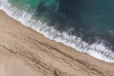 Aerial view of waves on the shoreline on an empty beach along the Atlantic Ocean coast in Sao Lourenco, Lisbon, Portugal. - AAEF20353