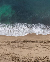 Aerial view of waves on the shoreline on an empty beach along the Atlantic Ocean coast in Sao Lourenco, Lisbon, Portugal. - AAEF20354