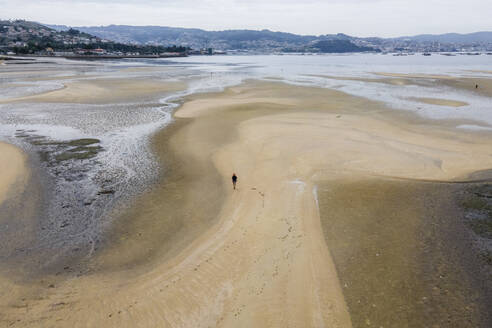 Luftaufnahme eines Spaziergängers am Strand bei Ebbe entlang der Küste von Moana, Vigo, Galicien, Spanien. - AAEF20473