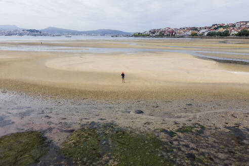 Luftaufnahme eines Spaziergängers am Strand bei Ebbe entlang der Küste von Moana, Vigo, Galicien, Spanien. - AAEF20474