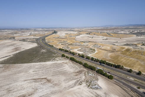 Aerial view of the highway crossing the desert valley near Monegros desert, Zaragoza, Spain. - AAEF20534