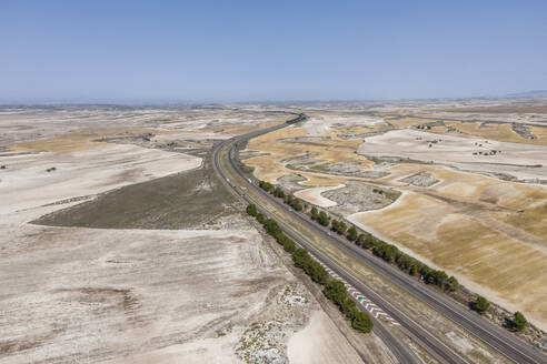 Aerial view of the highway crossing the desert valley near Monegros desert, Zaragoza, Spain. - AAEF20535