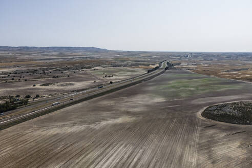 Aerial view of the highway crossing the desert valley near Monegros desert, Zaragoza, Spain. - AAEF20538