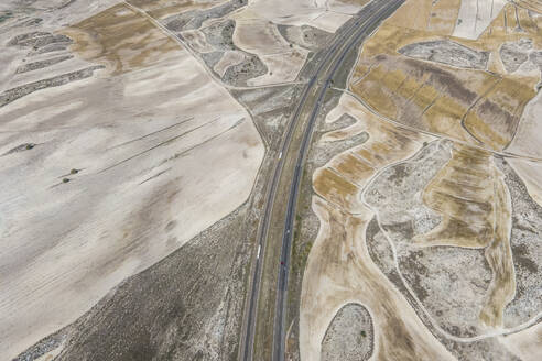 Aerial view of the highway crossing the desert valley near Monegros desert, Zaragoza, Spain. - AAEF20540
